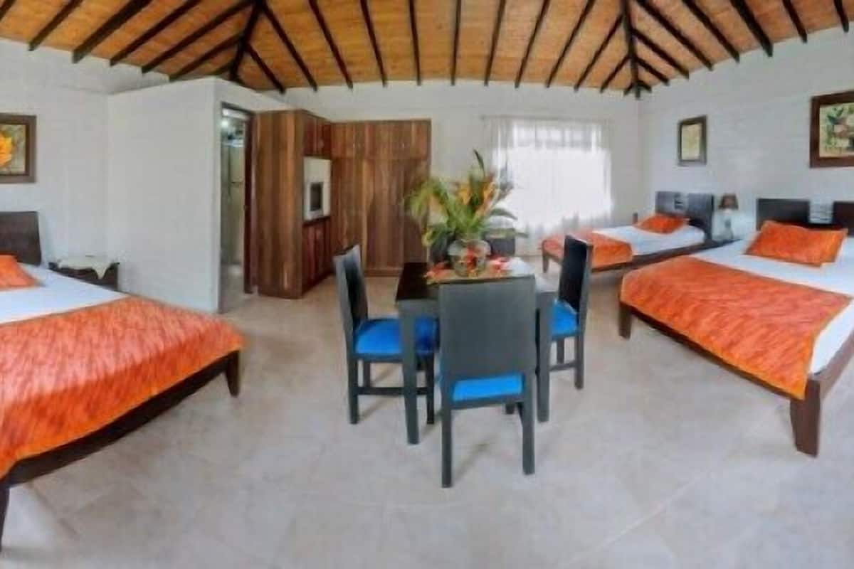 A hotel room with two beds, a dining table with chairs, and a kitchenette.