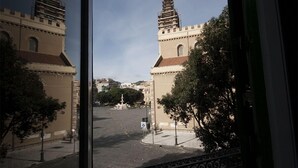 A view of a building with two towers, a paved street, and trees.