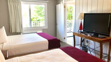 A hotel room with two beds, a television on a wooden table, and a window with curtains.