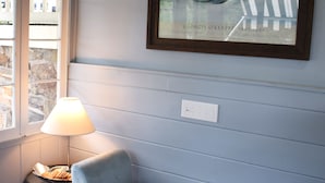 A room with a light blue bench, a lamp, and a framed painting on the wall. - Inn on the Hill (Lake George)