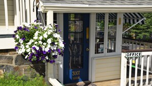 A front door with a blue door and a hanging flower basket. - Inn on the Hill (Lake George)