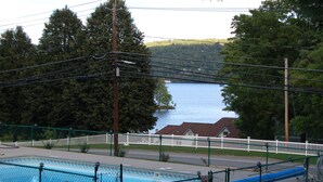 A swimming pool with a view of a lake and a white fence. - Inn on the Hill (Lake George)