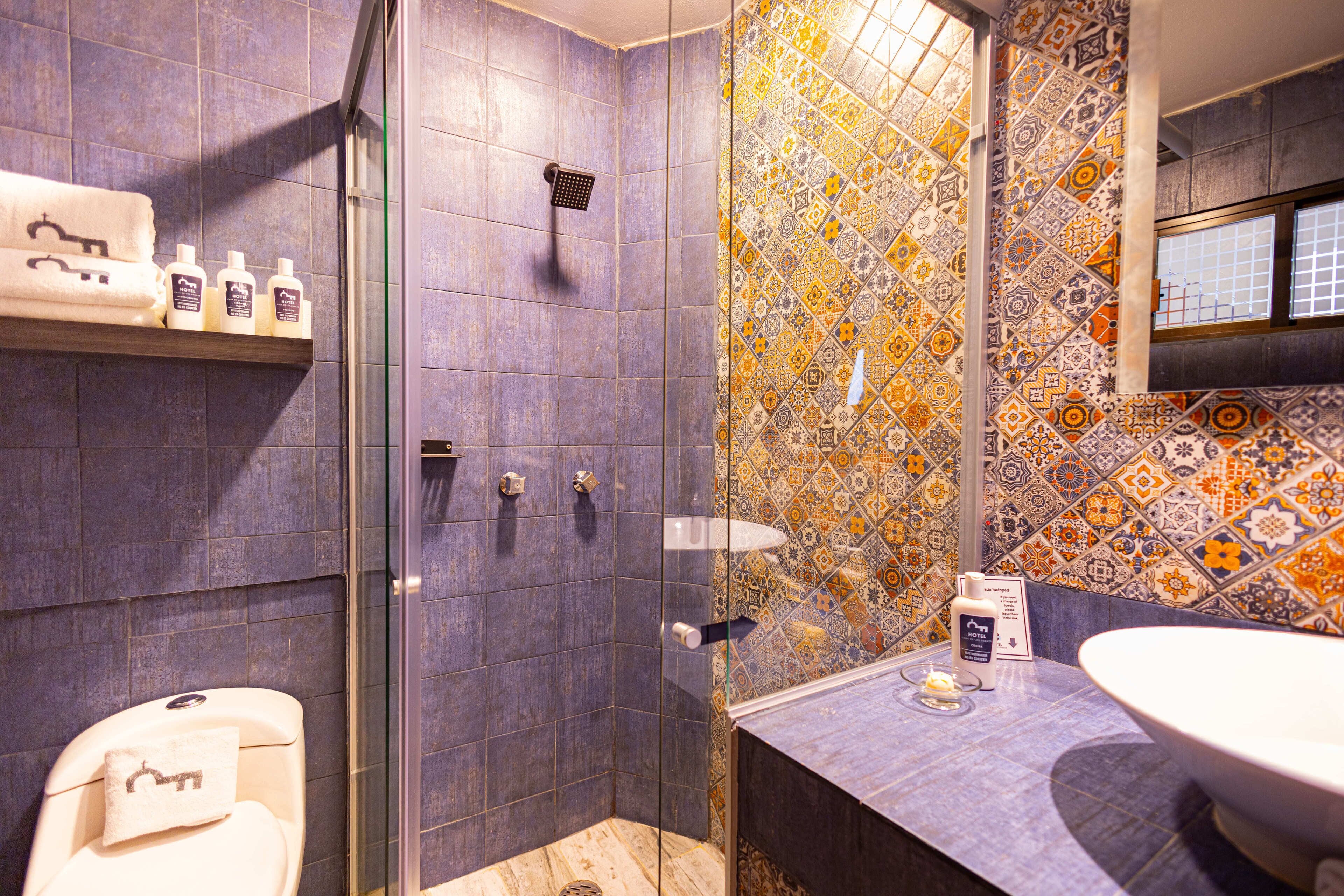A bathroom with a shower, a toilet, and a sink. There are toiletries on a shelf.