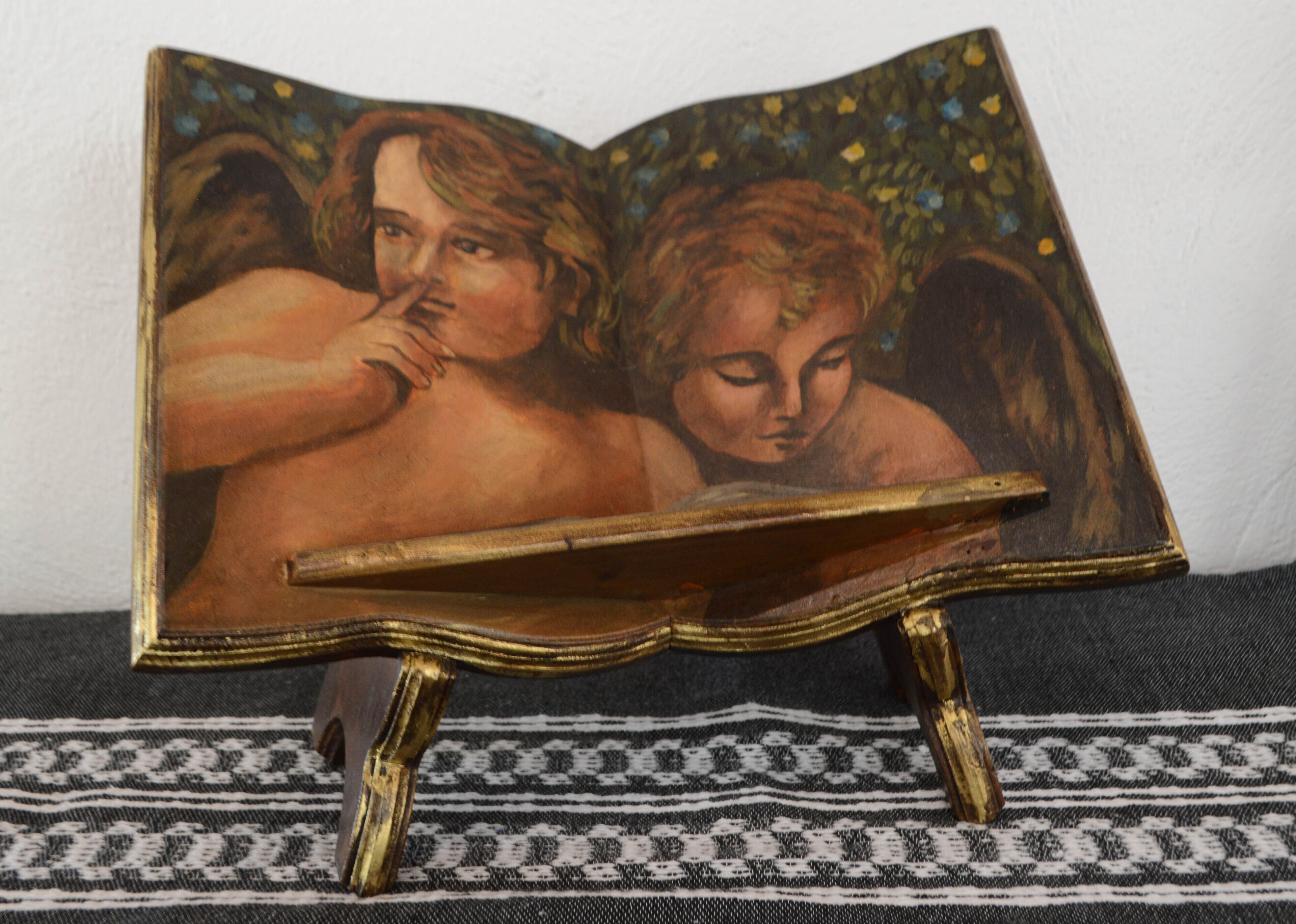 A book with a golden frame, open to a page with an angelic figure.