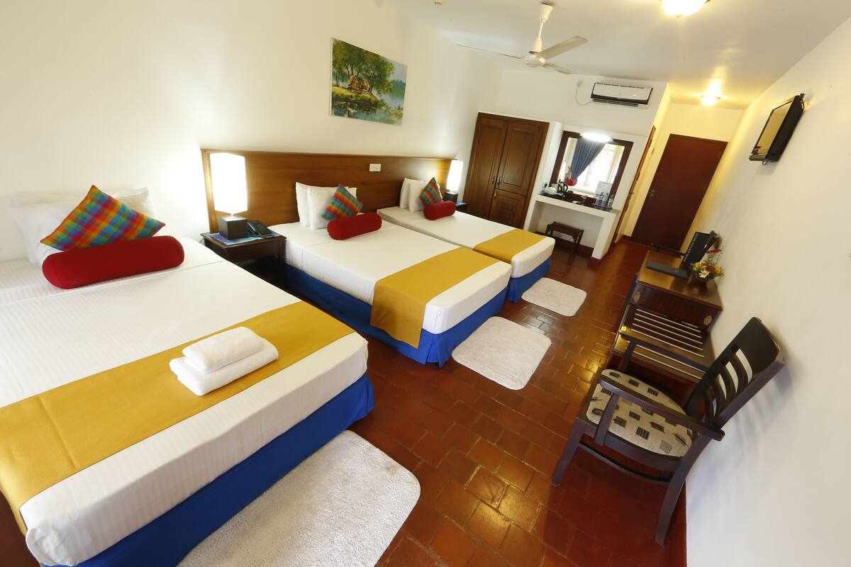 A hotel room with two beds, a desk, a chair, and a bathroom.