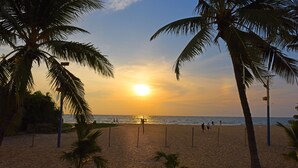 A beach with palm trees and a sunset.