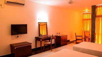 A hotel room with a bed, a desk with a chair, a television, and an air conditioning unit.
