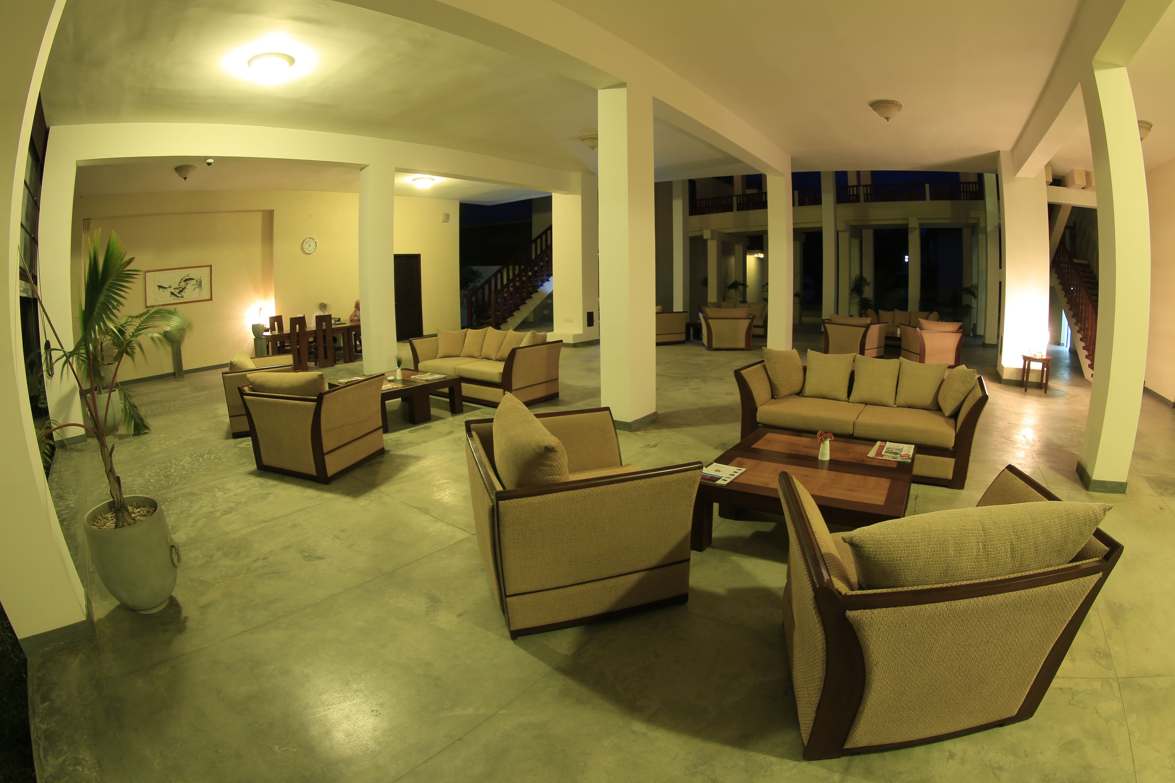 A spacious living area with multiple sofas and armchairs, a coffee table, and a potted plant.