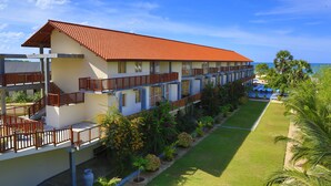 Un hotel con varios balcones, techo de tejas rojas y un césped bien cuidado.
