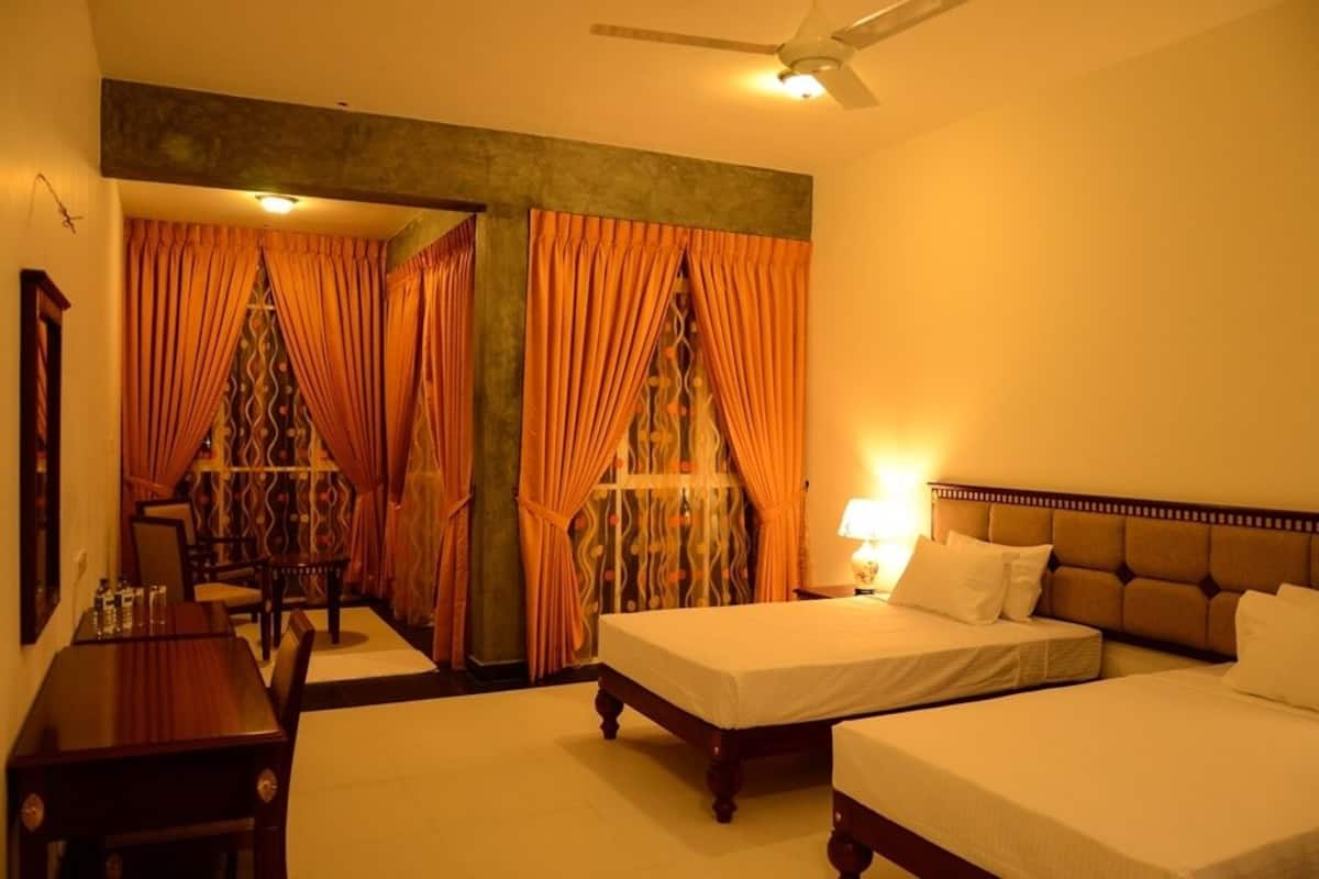 A hotel room with two beds, a desk, and a chair.