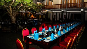 Un restaurante con una larga mesa de comedor lista para una comida, rodeado de sillas rojas.