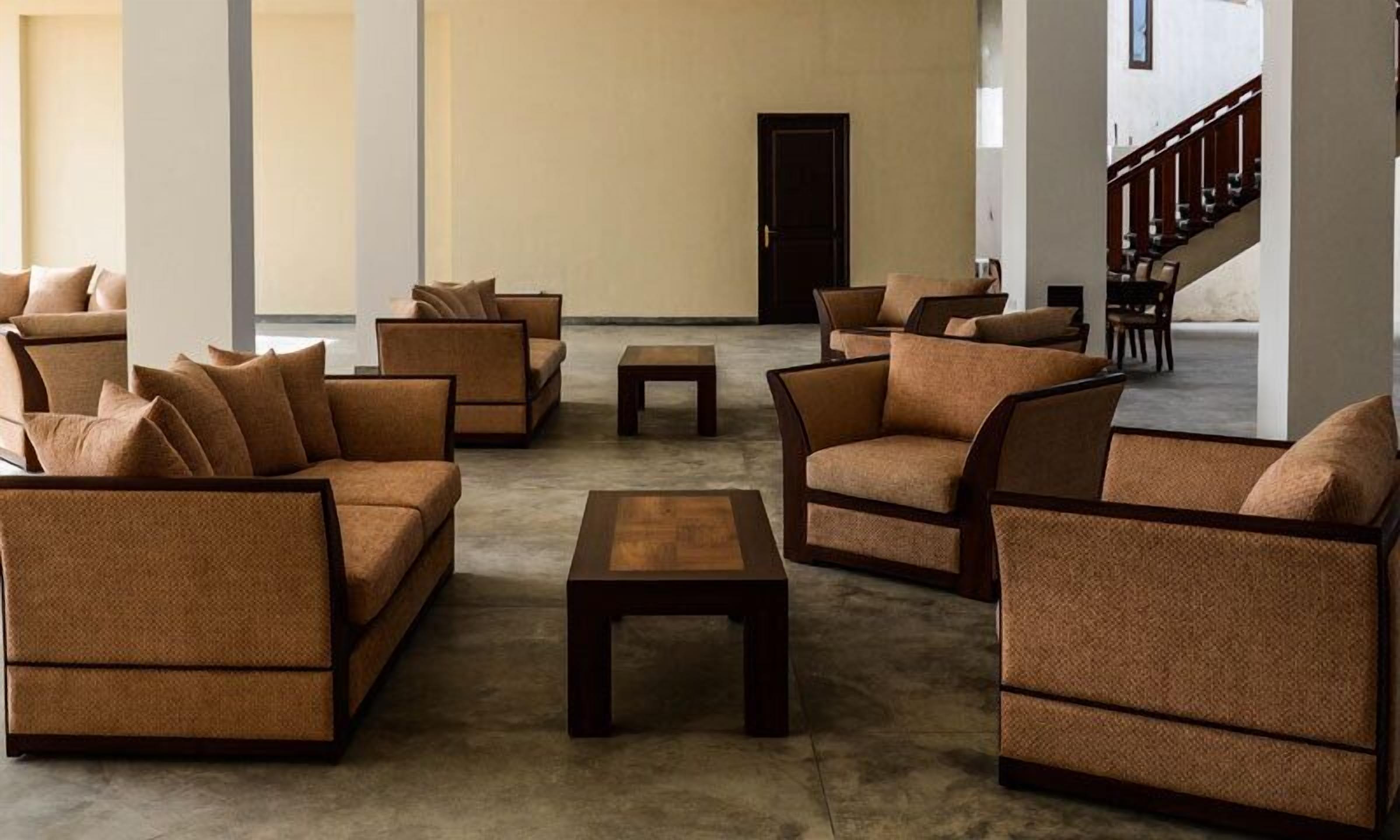 Um hall amplo com várias áreas de estar, incluindo sofás e poltronas, dispostas em torno de uma mesa de centro.