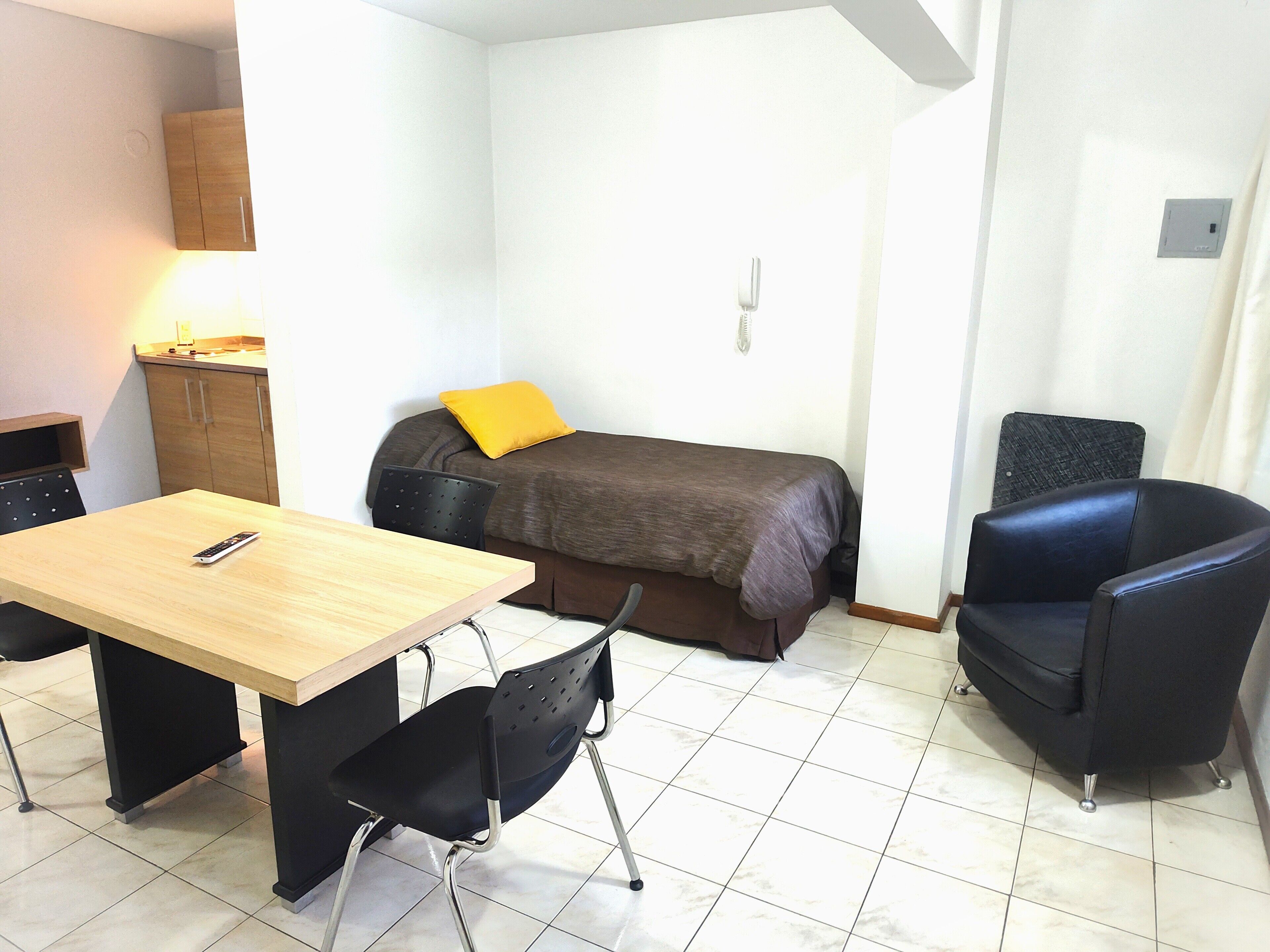 A small, clean room with a bed, a desk, and two chairs.