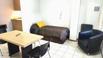 A small, clean room with a bed, a desk, and two chairs.