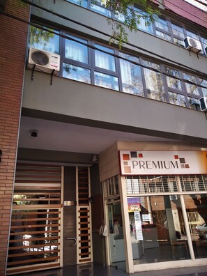 A building with a 'PREMIUM' sign, large windows, and an air conditioning unit.