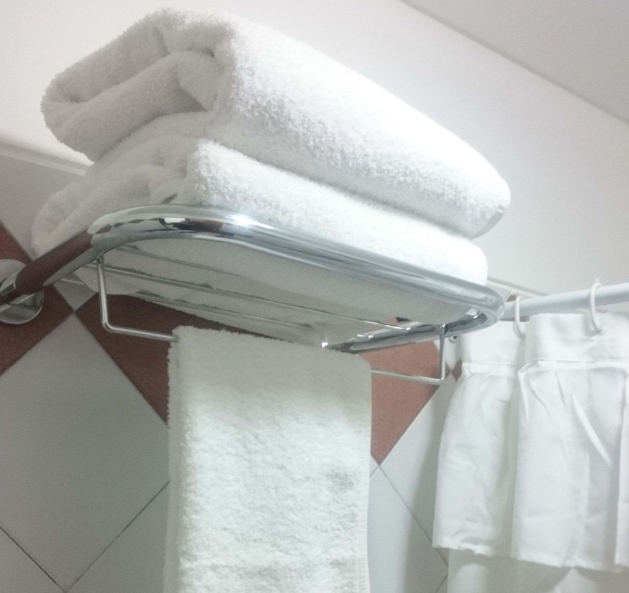 A bathroom with a towel rack holding folded towels and a hanging towel.