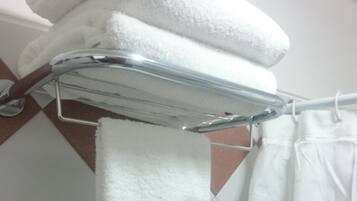 A bathroom with a towel rack holding folded towels and a hanging towel.