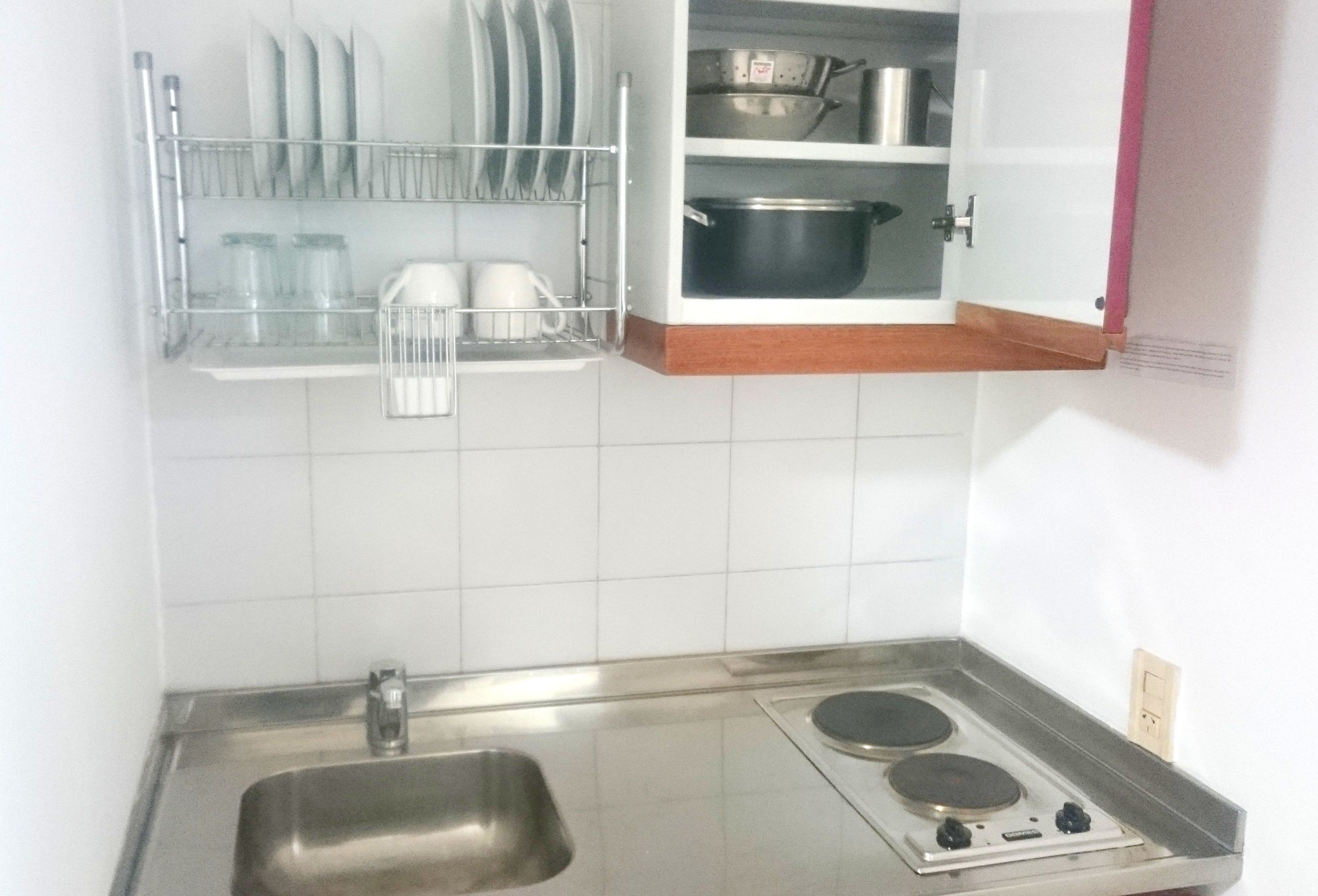 Cozinha com pia de aço inoxidável, duas bocas e escorredor de louça sobre o balcão.