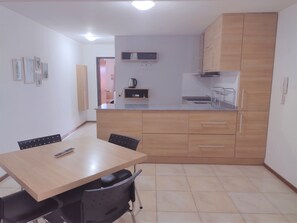 A compact kitchen with wooden cabinets, a countertop, and a dining area with a table and chairs.