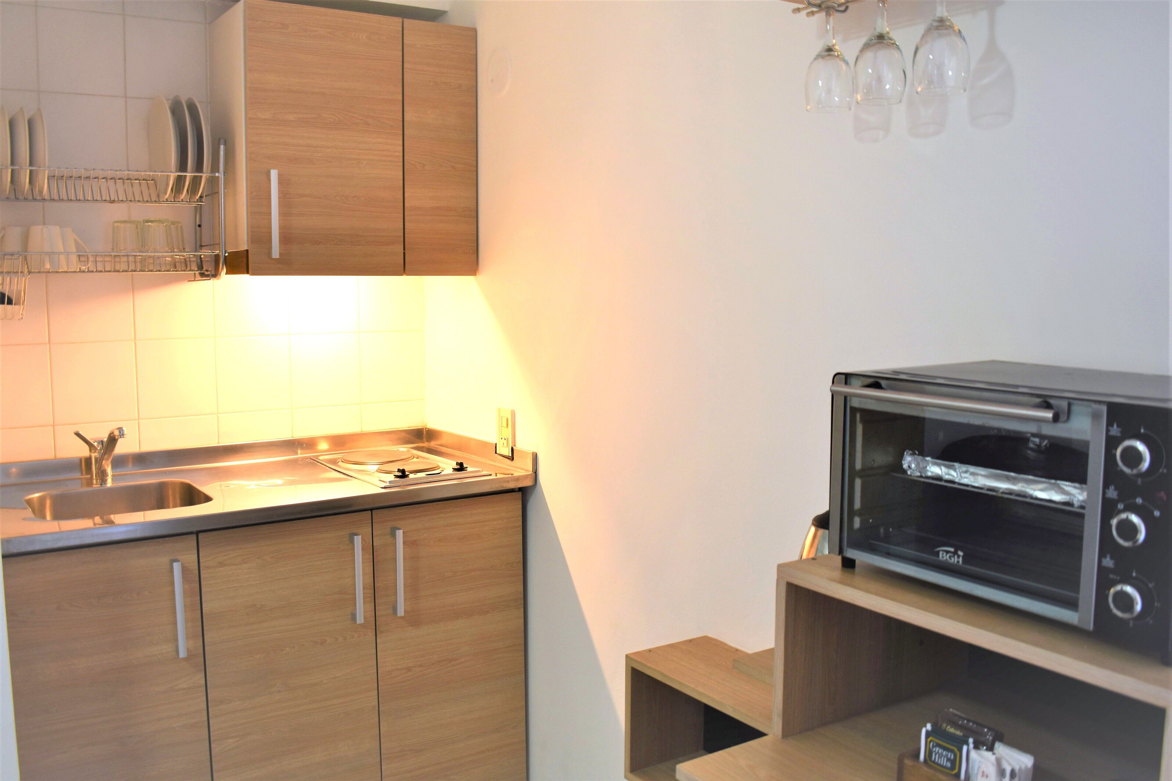 Una cocina moderna con armarios de madera, un lavamanos de acero inoxidable y un horno tostador integrado.