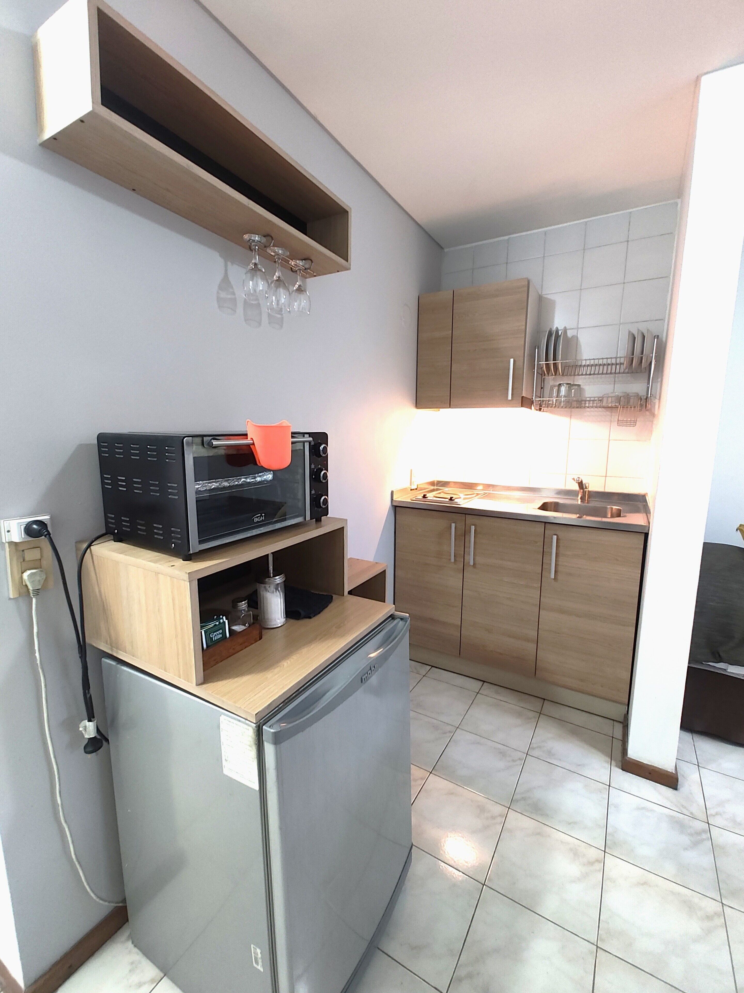 Una cocina compacta con refrigerador, microondas y armarios de madera.