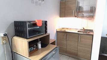 Una cocina compacta con refrigerador, microondas y armarios de madera.