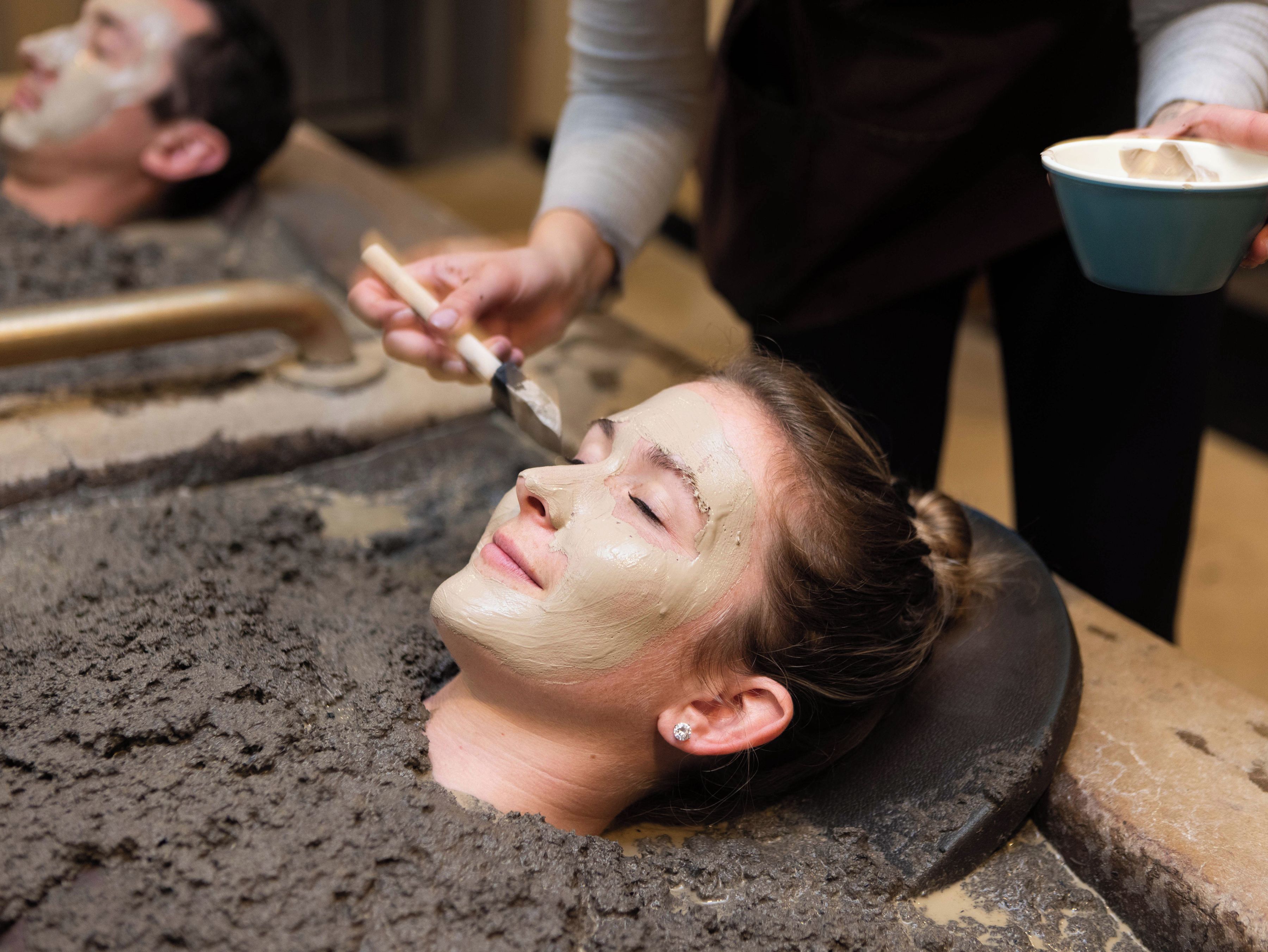 Een persoon ontvangt een gezichtsbehandeling met een masker op het gezicht.