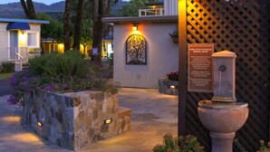 A stone pathway leading to a building with a tree mural and a sign about mineral water. - Golden Haven Hot Springs (Calistoga)