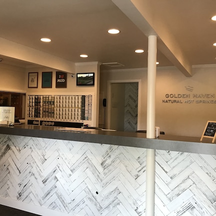 A reception area with a herringbone patterned wall, a counter with a sign, and a wall-mounted display of products.