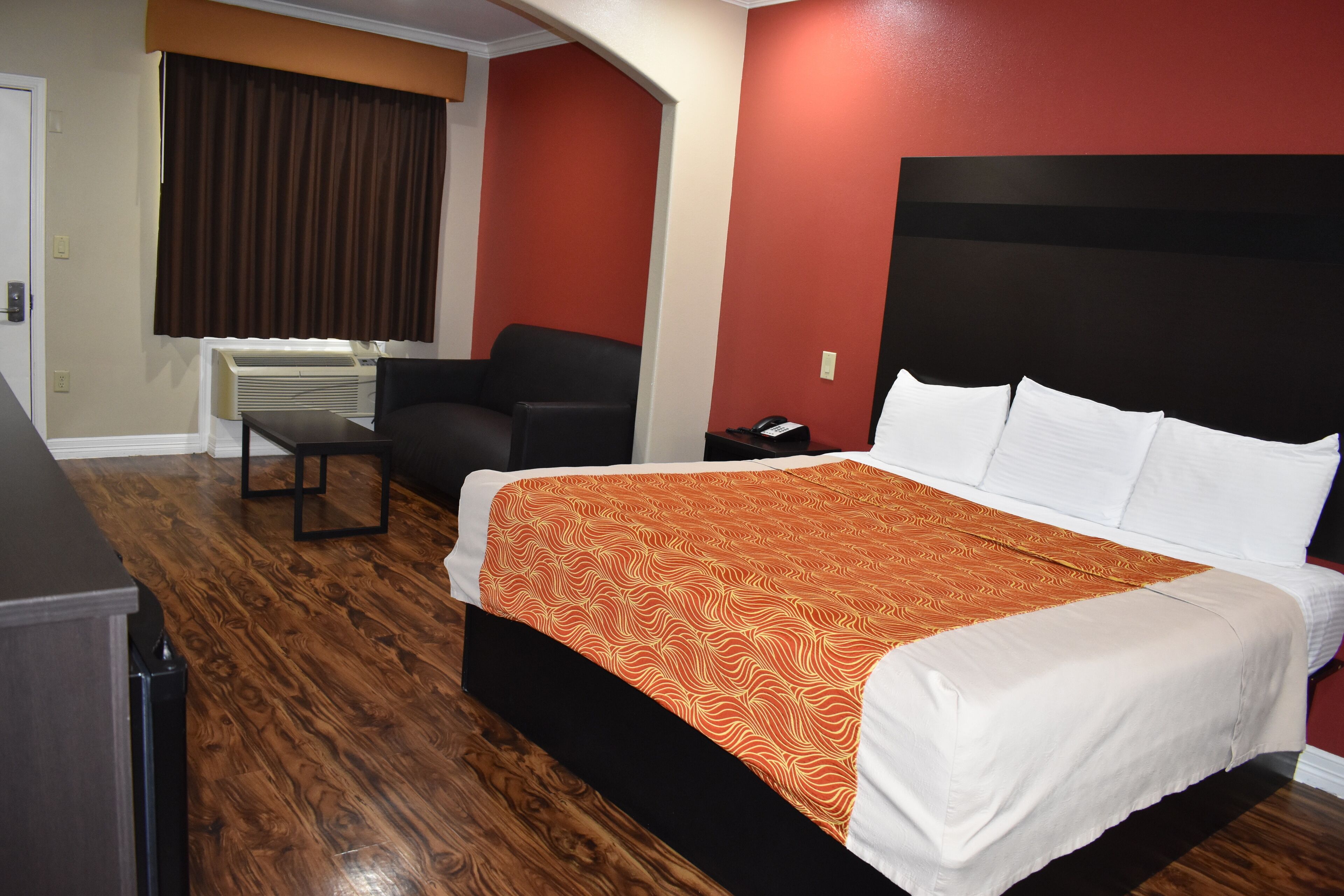 Een hotelkamer met een bed, een bureau, een stoel en een raam met gordijnen.