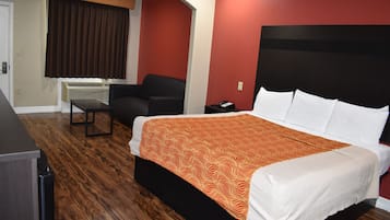 Een hotelkamer met een bed, een bureau, een stoel en een raam met gordijnen.