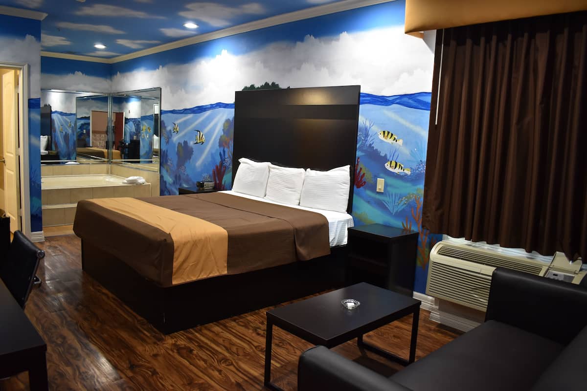 A hotel room with a bed, a desk, a chair, a mirror, and a wall mural.