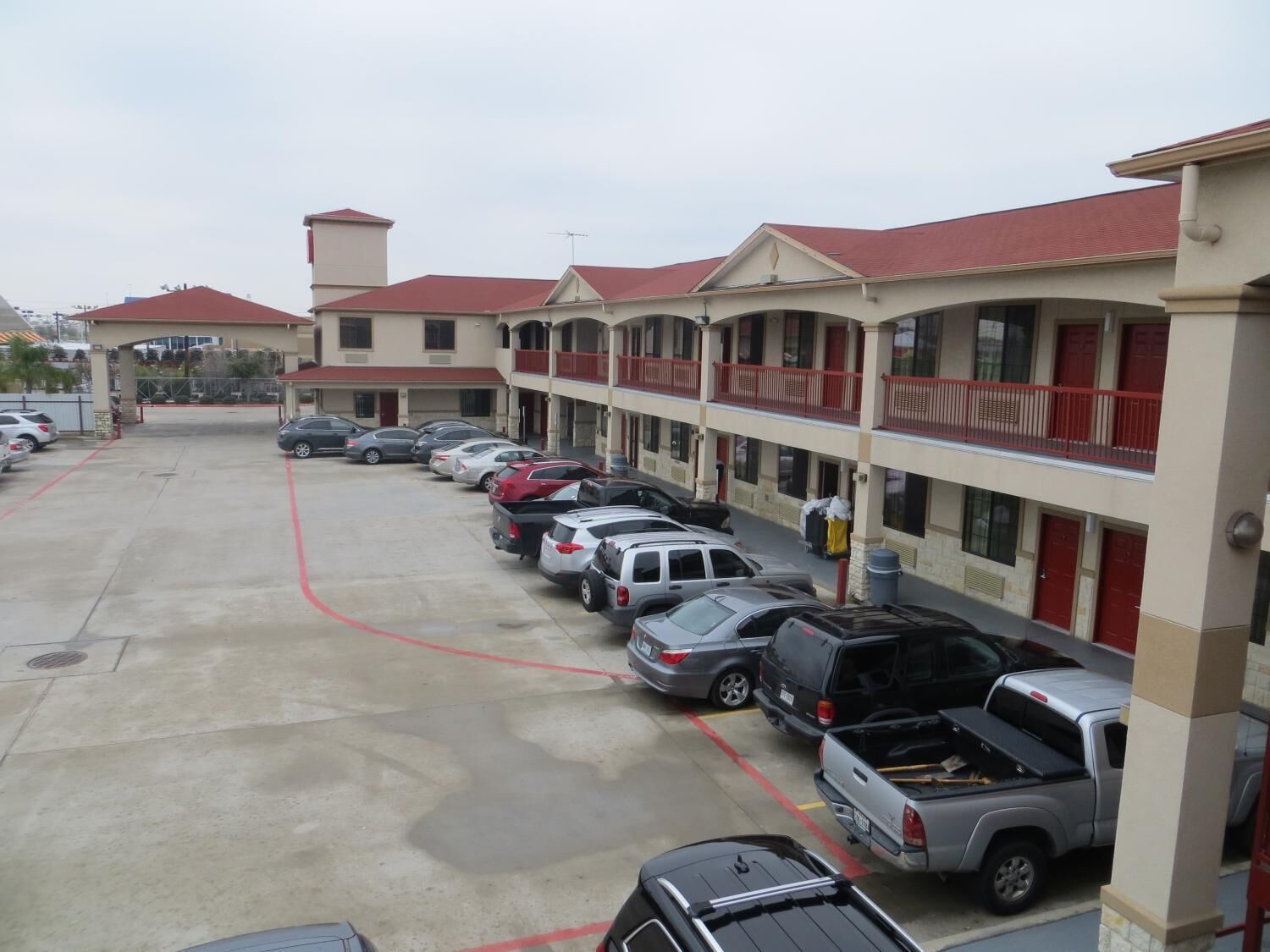 Un motel de varios pisos con una fila de coches estacionados en la entrada.