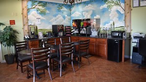 Een restaurant met een muurschildering van een landschap, houten stoelen, een koffiemachine en een koelkast.
