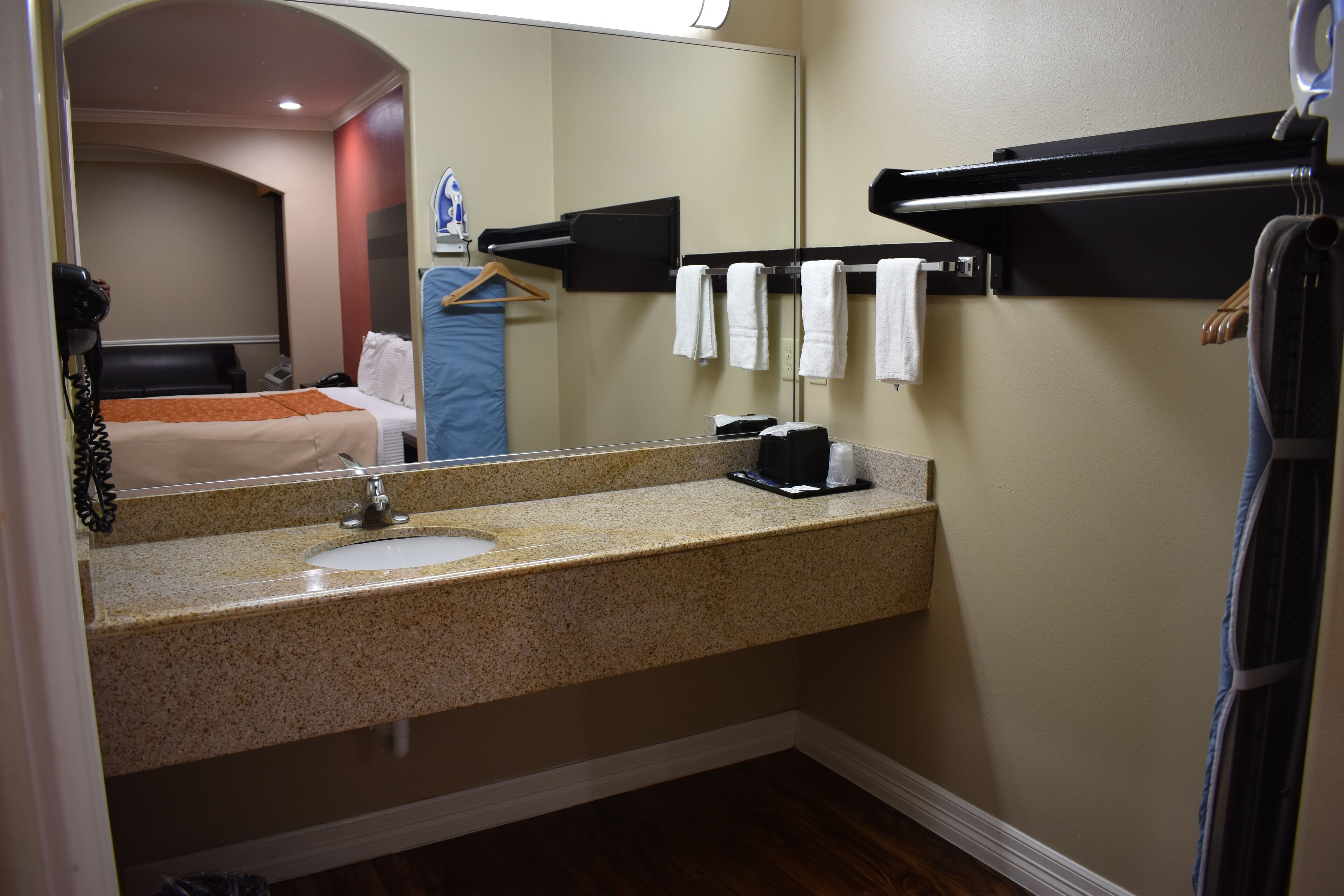 A hotel bathroom with a sink, mirror, towel rack, and a hairdryer.