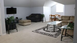 A living room with a flat-screen TV, two sofas, a coffee table, and a dining area with chairs. - Bent Tree Motel (Emory)
