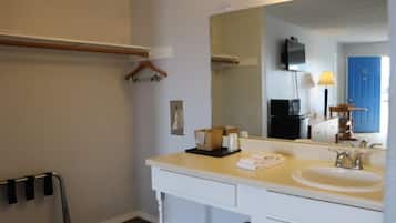 Een badkamer met een wit wastafelmeubel, een grote spiegel, een wastafel en een handdoekrek.