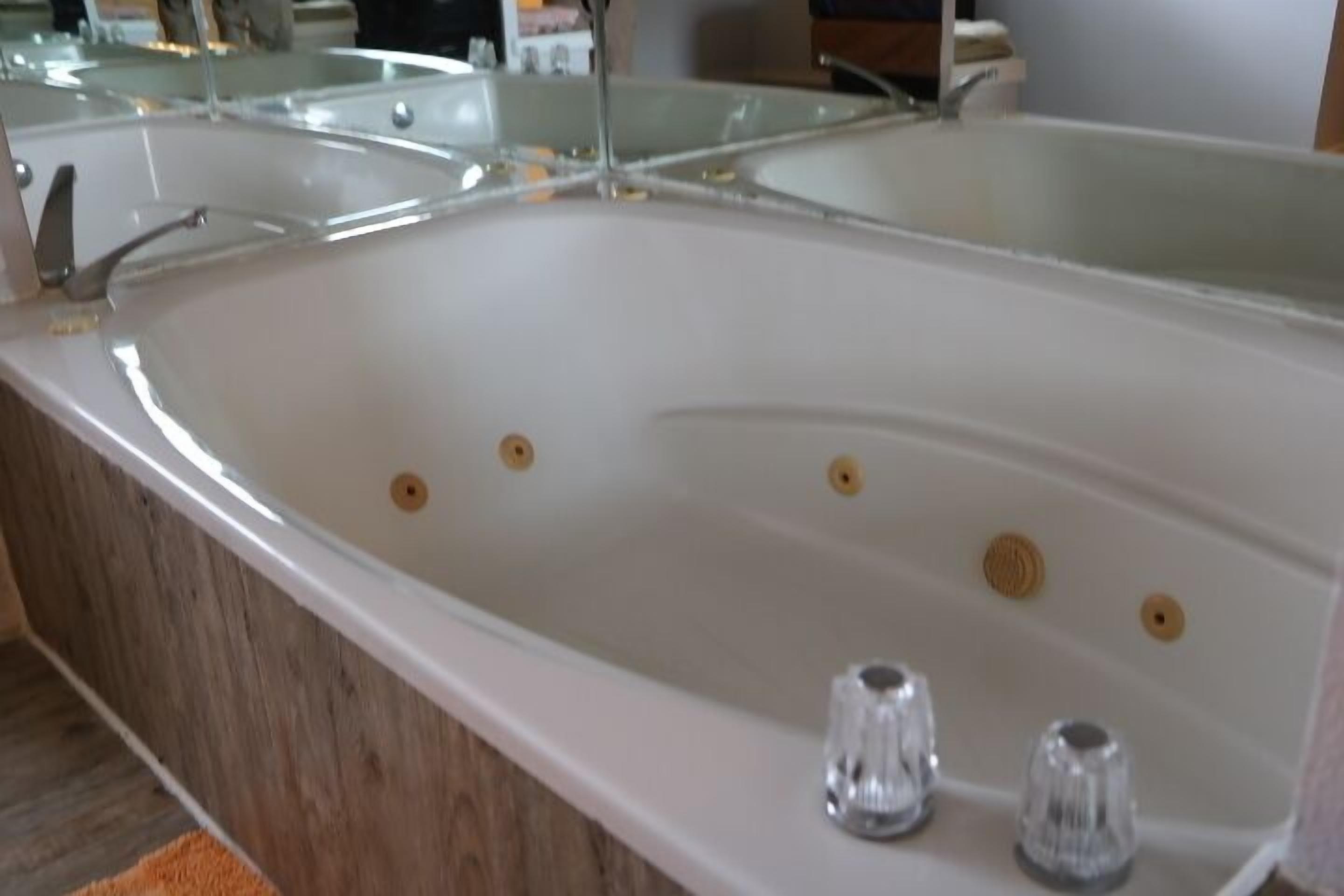 Een moderne badkamer met een groot bad, houten vloeren en een douchecabine van glas.