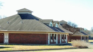 A row of brick buildings with pitched roofs and a covered porch area. - Bent Tree Motel (Emory)