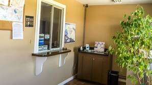 A reception area with a counter, a window, a map, and a plant. - Bent Tree Motel (Emory)