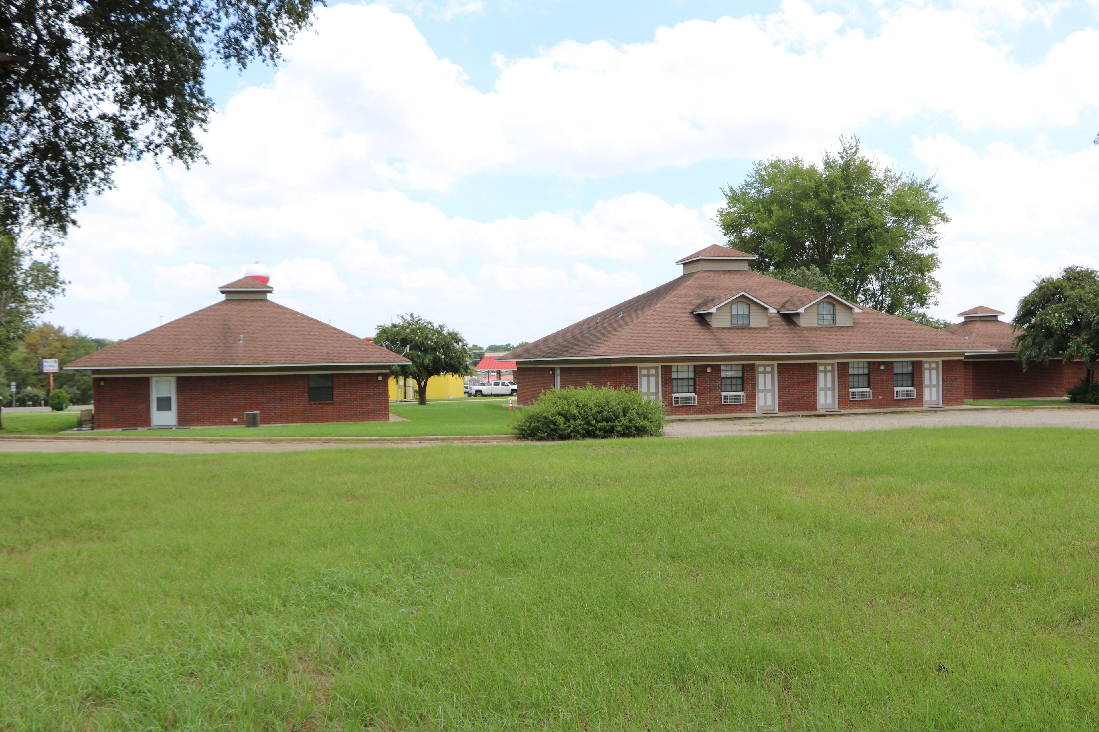 A brick building with a red roof, a small front lawn, and a tree to the left.