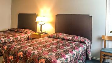 Une chambre d’hôtel avec deux lits, une table de chevet avec une lampe et une chaise.