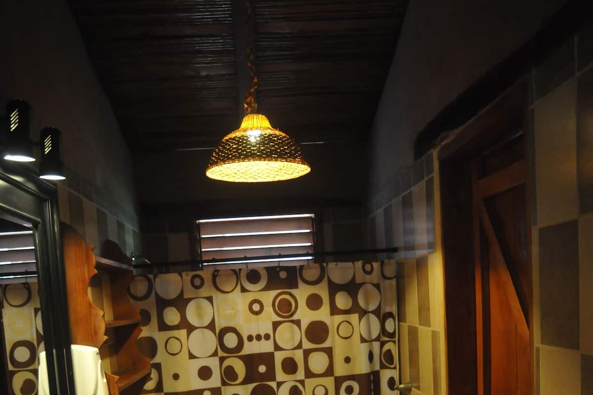 A bathroom with a patterned wall, a sink, a toilet, and a hanging light fixture.