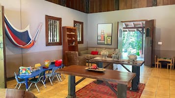 Relax in a cozy living area with a hammock, sofa, and dining table, surrounded by natural views.
