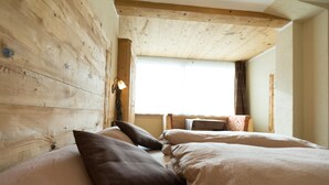 Een houten kamer met twee bedden, een raam en een lamp.