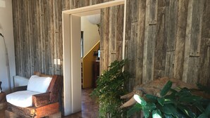 A room with a wooden wall, a white sofa, a wooden coffee table, and a potted plant. - Nativa Hotel Boutique (Santiago)