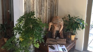 A room with a rustic wooden wall, a wooden elephant sculpture, and several potted plants. - Nativa Hotel Boutique (Santiago)