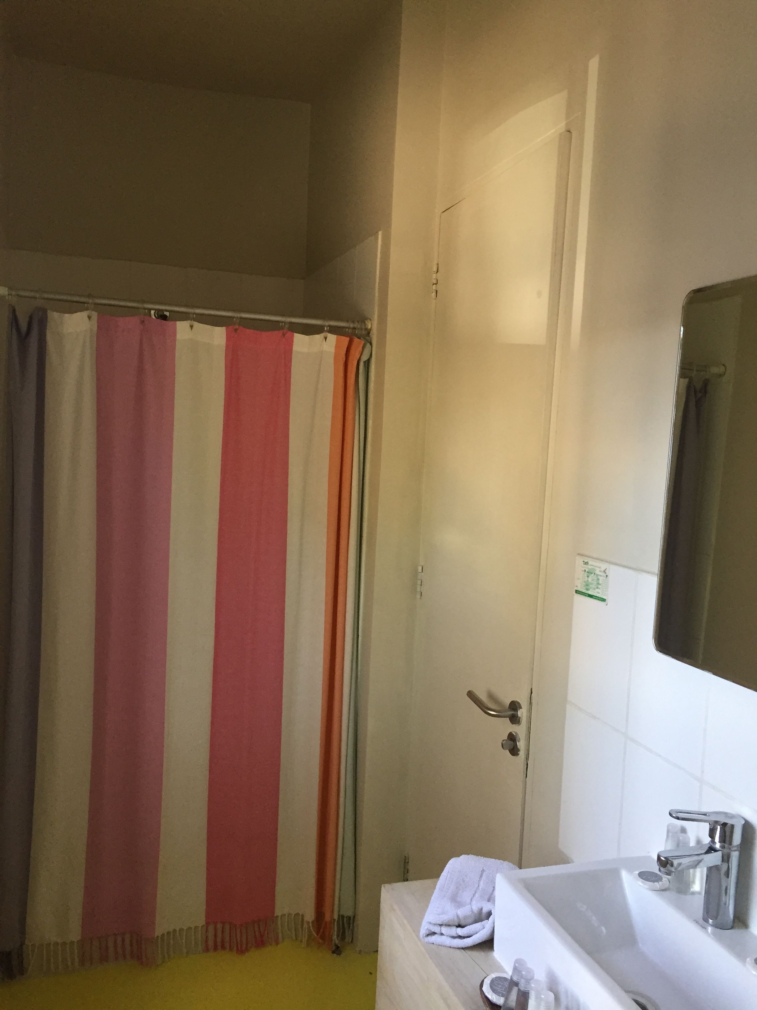 A bathroom with a shower curtain, a sink, and a mirror.