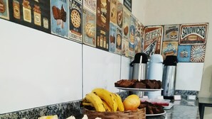A kitchen counter with a variety of fruits and baked goods, including sliced bananas, apples, and bread. - Dok Brasília Hotel - Unidade Taguatinga (Águas Claras)