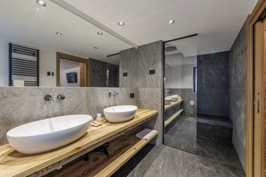 A modern bathroom with two large sinks, a wooden vanity, and a glass-enclosed shower area. - Hotel Steinbock (Livigno)